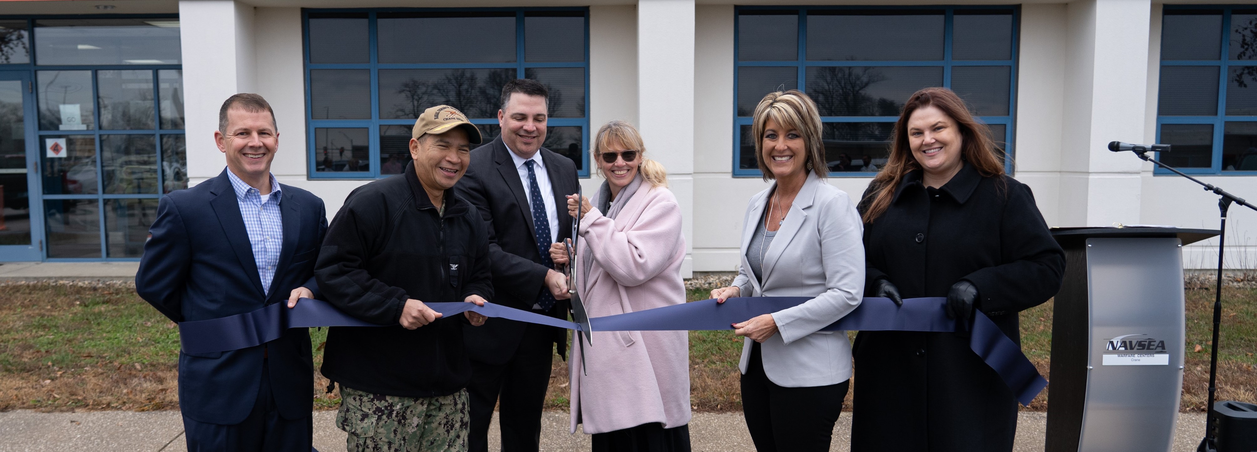 Navy and NSWC Crane leaders stand for a ribbon cutting ceremony.